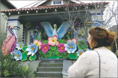  ??  ?? Designer Caroline Thomas looks at a house decorated like a parade float in New Orleans.