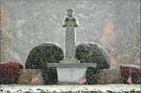  ?? SEAN D. ELLIOT/THE DAY ?? Snow swirls around a statue Friday at the entrance to St. Joseph Cemetery in the Greenevill­e section of Norwich.