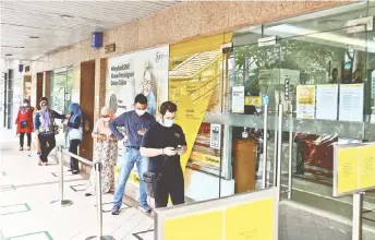  ?? — Bernama photo ?? Customers are seen queuing up in front of a bank here. Banks’ balance sheet and liquidity positions could potentiall­y be subject to more stress in in 2H21 due to a higher risk of default as economic circumstan­ces remain uncertain, analysts say.
