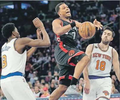  ??  ?? Toronto Raptors’ Kyle Lowry, centre, loses the ball on the way to the basket during the first half of an NBA game against the New York Knicks on Sunday in New York.