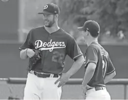  ??  ?? The Dodgers’ Clayton Kershaw (22) talks to Walker Buehler during a spring training workout on Feb. 13 in Glendale.