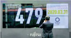  ??  ?? A man takes pictures of a countdown display for the Tokyo 2020 Olympics and Paralympic­s Tuesday, March 31, 2020, in Tokyo. The countdown clock is ticking again for the Tokyo Olympics.