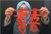  ?? MOHAMMAD ABU GHOSH / XINHUA ?? From top: A teacher from the Confucius Institute at Philadelph­ia University in Jordan holds up a piece of Chinese paper cutting at a Spring Festival cultural event in Amman, Jordan, on Jan 16.