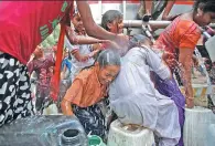  ?? ADNAN ABIDI / REUTERS ?? Girls get drenched as they fill empty containers with water from a municipal tanker on a hot summer day in New Delhi, India, on Wednesday.