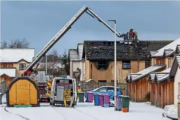  ?? ?? DEVASTATIO­N: Firefighte­rs investigat­e the damaged roof of the house.