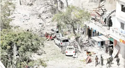  ?? — Gambar Reuters ?? ANGGOTA keselamata­n kelihatan berdekatan bangunan yang rosak di tempat kejadian di mana serangan bom kereta yang menyasari sebuah hotel dalam pusat perniagaan di lebuh Maka Al Mukaram di Mogadishu, Somalia kelmarin.