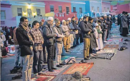  ??  ?? Our history: Men pray after breaking the fast during the holy month, when Bo-Kaap residents filled the streets to reassert their ownership of the suburb renowned for its colourful houses. Photo: Rodger Bosch/AFP