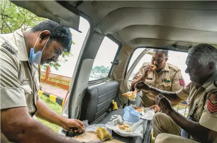  ?? ATUL LOKE/THE NEW YORK TIMES ?? Officers grab a bite to eat March 20 in a van in Port Blair, the capital of the island territory of Andaman and Nicobar in India.