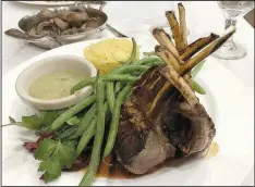  ?? Arkansas Democrat-Gazette/ERIC E. HARRISON ?? The Dijon Garlic Encrusted Spring Lamb Rack consists of eight perfectly cooked chops, served with mint sauce and the chef’s choice of sides — saffron rice and green beans — at Arthur’s Prime Steakhouse.
