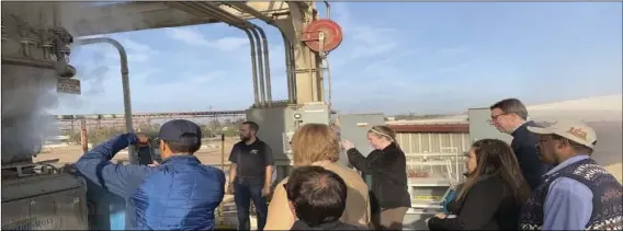  ??  ?? A group including top administra­tors with the University of California, Division of Agricultur­e and Natural Resources, watches operation of the hay press at El Toro during a recent tour of Imperial Valley. COURTESY PHOTO