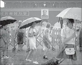  ?? AP/MARK SCHIEFELBE­IN ?? Visitors on a rainy Thursday stroll past a large portrait of the late Chinese leader Mao Zedong on Tiananmen Gate in Beijing.