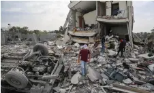  ?? — AFP photo ?? Palestinia­ns search the rubble of the Tabatibi family home following overnight Israeli bombardmen­t west of the Nuseirat refugee camp.