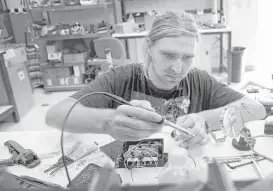  ??  ?? Blue River engineer Charlie Ross solders components for sensors used for a drone. Blue River is a Sunnyvale, Calif., startup developing farm equipment using computers and robotics meant to detect every plant on a farm.