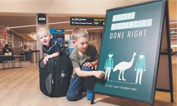  ?? Picture: BRENDAN RADKE ?? POINTERS: Lachlan McLean, 2, and Euan McLean, 7, check out a sign at Cairns Airport telling people to stay at least one cassowary apart.