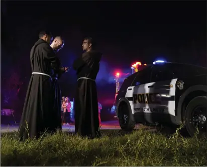  ?? PHOTOS BY ERIC GAY — THE ASSOCIATED PRESS ?? Priests gather near the scene where officials say dozens of people were found dead and multiple others were taken to hospitals with heatrelate­d illnesses Monday after a semitraile­r containing suspected migrants was found in San Antonio.