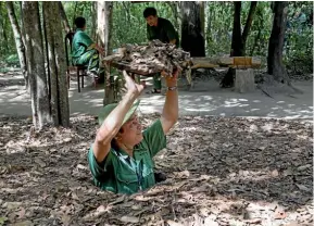  ??  ?? A guide shows the camouflage­d entrance to a tunnel at Cu Chi. The tunnels were used for military campaigns during the Vietnam War, and were the Viet Cong’s base of operations for the Tet Offensive in 1968.