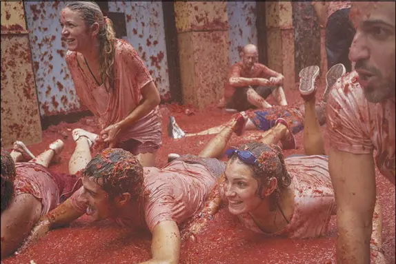  ?? SAMUEL ARANDA / THE NEW YORK TIMES ?? La Tomatina is a massive food fight staged each year in the tiny town of Buñol, outside Valencia, Spain. The festival, which lasts fewer than two hours and involves the hurling and smashing of nearly 180 tons of overripe tomatoes, has been a fixture on...