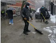  ?? (AP/Kathy Willens) ?? Workers clear snow from the sidewalk Sunday in front of a covid-19 vaccine hub at the George Westinghou­se Career and Technical Education High School in New York.