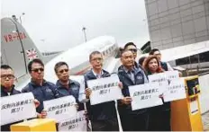  ?? Bloomberg ?? Representa­tives of Cathay Pacific workers hold signs during a protest at Cathay Pacific City, Cathay Pacific Airways Ltd’s headquarte­rs, in Hong Kong, China yesterday.