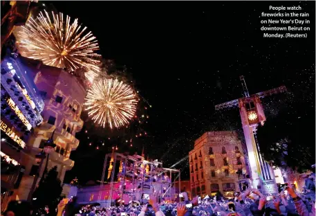  ??  ?? People watch fireworks in the rain on New Year's Day in downtown Beirut on Monday. (Reuters)