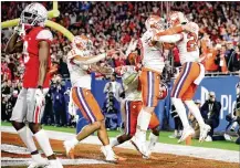  ?? CHRISTIAN PETERSEN / GETTY IMAGES ?? Clemson’s Nolan Turner (far right) is congratula­ted by his teammates after intercepti­ng the ball in the final minute of the game against Ohio State Buckeyes in the College Football Playoff Semifinal on Saturday in Glendale, Ariz.
