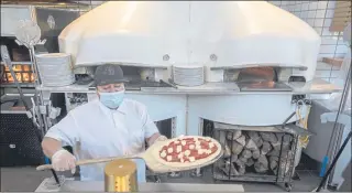  ??  ?? Erick Gonzalez prepares a margherita pizza for the Italian ovens at Rise Woodfire restaurant in the San Mateo Caltrain station.