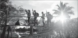  ?? Fernando Vergara Associated Press ?? FARC rebels walk over a bridge in southern Colombia this month. Under terms of the agreement with the government, the group will get 10 congressio­nal seats.