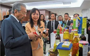  ??  ?? Important commodity: Primary Industries Minister Teresa Kok showing Dr Mahathir some of the various palm oil products on display at the Parliament building. — Bernama