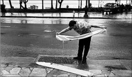  ?? JOHN LOCHER/AP ?? Kevin Pak empties hydro barriers, used to block water much like a sandbag, as he helps reopen a store Saturday along Waikiki Beach in Honolulu. Lane veered from the islands.