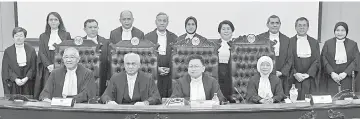  ??  ?? Malanjum (seated second right) posing with the 10 judicial commission­ers after taking their oath.