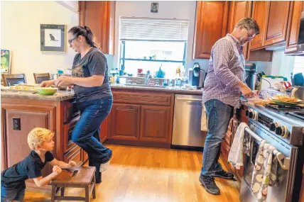  ?? MELINA MARA/WASHINGTON POST ?? Aimee Rae Hannaford makes cookies with her husband, Tom Baker, while keeping an eye on their 3-yearold son Ryan at their home in Castro Valley, California.