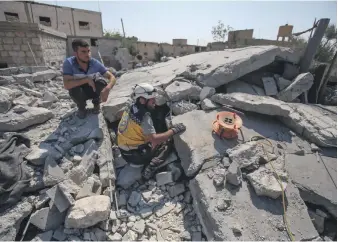  ?? AFP ?? Members of the Syrian Civil Defence (White Helmets) search for victims at the site of a reported air strike on the village of Deir Sharqi in Syria’s northern province of Idlib yesterday