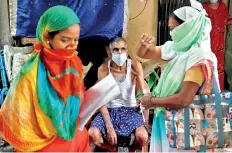  ??  ?? Community health volunteers check the pulse of a resident during a check-up campaign for COVID-19 in Mumbai. (Reuters)