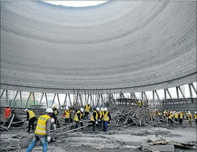  ?? Picture: AFP ?? CRUSHING TRAGEDY: Workers search through the remains of a collapsed platform in a cooling tower at a power station at Fengcheng in China’s Jiangxi province yesterday. At least 40 people were killed