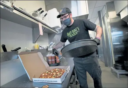  ?? AUSTIN FLESKE / Loveland Reporter-herald ?? Dan Geller, manager at the new Krazy Karl’s Pizza in Loveland, puts a freshly baked pizza into a box Thursday. The Fort Collins pizza shop opened its Loveland location March 1.