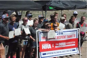  ??  ?? NRA_Awards: Cache Valley Crushers team recipients of NRA Marksmansh­ip Qualificat­ion awards stand for photos by an NRA banner with their certificat­es during the awards ceremony on June 3, 2018.