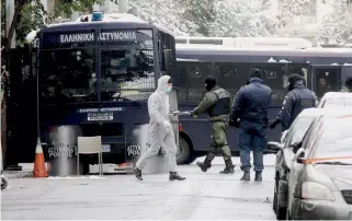  ??  ?? Police officers and forensic experts walk outside PASOK party headquarte­rs in central Athens after a gunman opened fire at a police bus yesterday. A police officer was slightly injured in the attack, which took place shortly after 6 a.m.