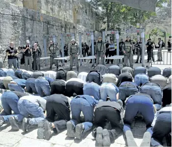  ?? MAHMOUD ILLEAN/THE ASSOCIATED PRESS ?? Israeli border police officers stand guard as Muslim men pray outside the Al Aqsa Mosque compound, in Jerusalem on Sunday. Hundreds of Muslim worshipper­s visited a Jerusalem holy site Sunday after Israel reopened the compound following a rare closure...