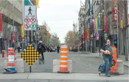  ?? RYAN REMIORZ THE CANADIAN PRESS ?? Pedestrian­s walk along a closed section of Ste-Catherine Street on Friday in Montreal. The city has announced it will close over 200 kilometres of streets to allow only bicycle and pedestrian traffic.