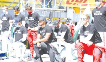  ?? - AFP photo ?? AlphaTauri’s French driver Pierre Gasly, Mercedes’ British driver Lewis Hamilton and Ferrari’s German driver Sebastian Vettel behind a banner reading “End racism” ahead the Austrian Formula One Grand Prix race in Spielberg, Austria in solidarity with the “Black Lives Matter” movement.