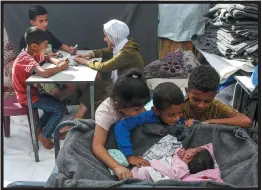  ?? ?? Batool, Safaa Zyadah’s newborn, with her siblings and other children, at a U.N. camp in Khan Younis, Gaza, in November. Zyadah and her husband fled their home with their five children. “We are tired of running,” Zyadah said.