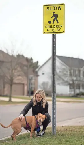  ?? JOSEPH SCHELLER/COLUMBUS DISPATCH ?? Lindsay Guard pets her 7-year-old pit bull mix, Gracie, after posing for a portrait near the intersecti­on of Spring Run Drive and Dunaway Lane in Genoa Township. Guard is concerned the township is being forced to remove stop signs from neighborho­od intersecti­ons.