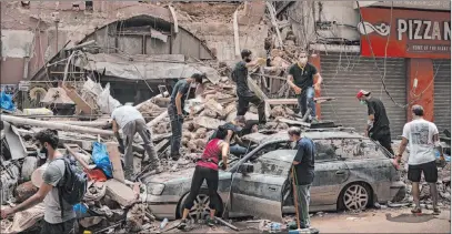  ?? Felipe Dana The Associated Press ?? People remove debris from a house damaged by Tuesday’s explosion in Beirut. Rescue teams were searching the rubble of Beirut’s port for bodies Friday, after the massive blast sent a wave of destructio­n through Lebanon’s capital.