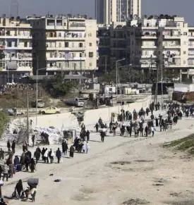  ?? REUTERS ?? CIVILIANS carry their belongings as they walk at the Karaj al-Hajez crossing.