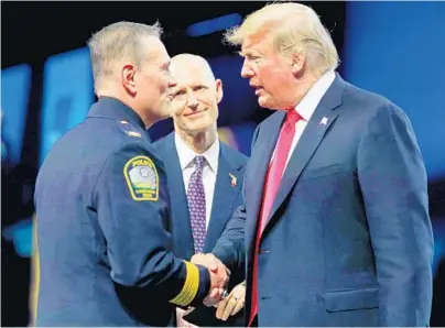  ?? PHOTOS BY JOE BURBANK/ORLANDO SENTINEL ?? Internatio­nal Associatio­n of Chiefs of Police President Louis M. Dekmar, from left, and Gov. Rick Scott welcome President Donald Trump before he delivers remarks at the police organizati­on’s annual conference Monday at the Orange County Convention Center.