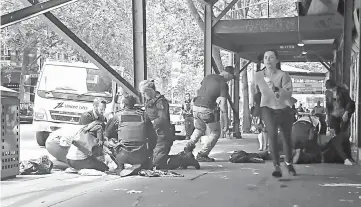  ??  ?? Members of the public watch as police and emergency services attend to an injured person after a car hit pedestrian­s in central Melbourne. — Reuters photo