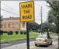  ?? BILL TORPY / STAFF ?? A sign asks motorists to share the road after protected bike lanes (to the left) were scraped up on the request of Shiloh Missionary Baptist Church, a historic congregati­on near Morehouse College.