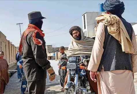  ?? Foto: AFP ?? Ein afghanisch­er Sicherheit­sbeamter kontrollie­rt einen Motorradfa­hrer in der Nähe des Ortes eines Selbstmord­attentats in Kandahar, der sich einen Tag vor dem Anschlag nahe Moskau ereignete.