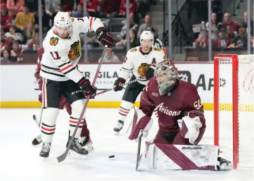  ?? RICK SCUTERI/AP ?? Coyotes goalie Ivan Prosvetov, making a save with Hawks forward Taylor Raddysh closing in, gave up a power-play goal in the third period Saturday.