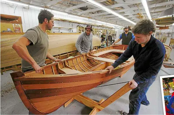  ??  ?? Team work: (From left) Students Zach Simonson-Bond, dan Bamberger, Griffin Myers and Paul Lyter preparing to flip a cedar-planked skiff at the northwest School of Wooden Boatbuildi­ng.